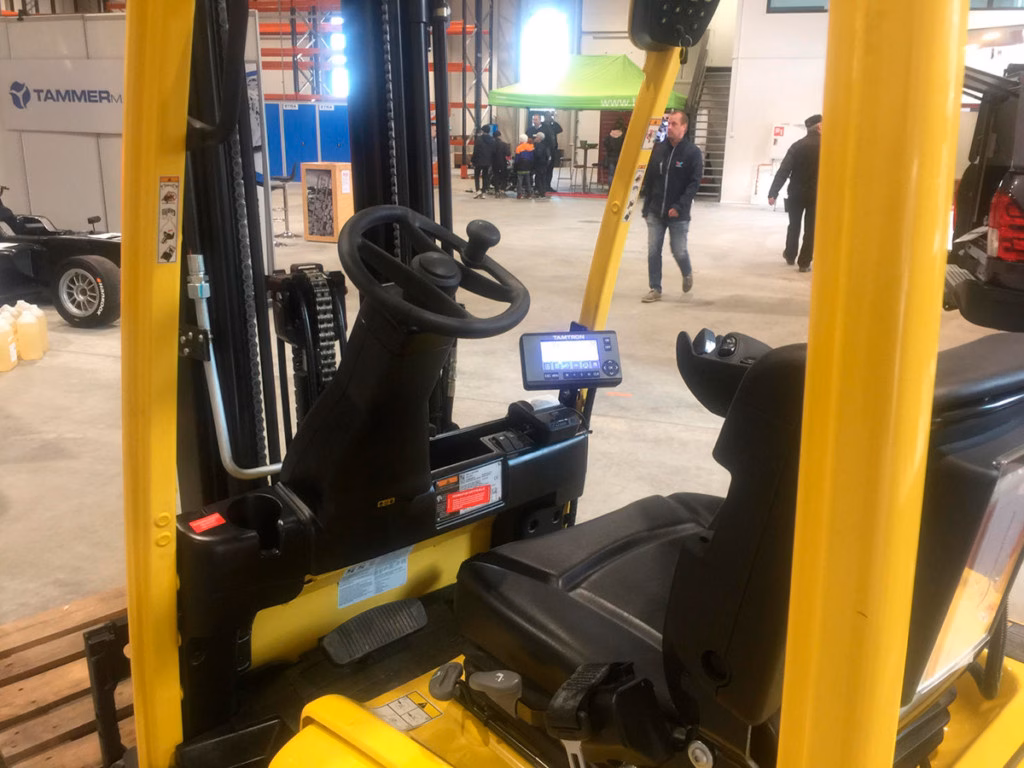 Ein robuster Gabelstapler mit einer integrierten hydraulischen On-Board-Waage von Tamtron beim Wägen einer Palette im Logistikzentrum.
